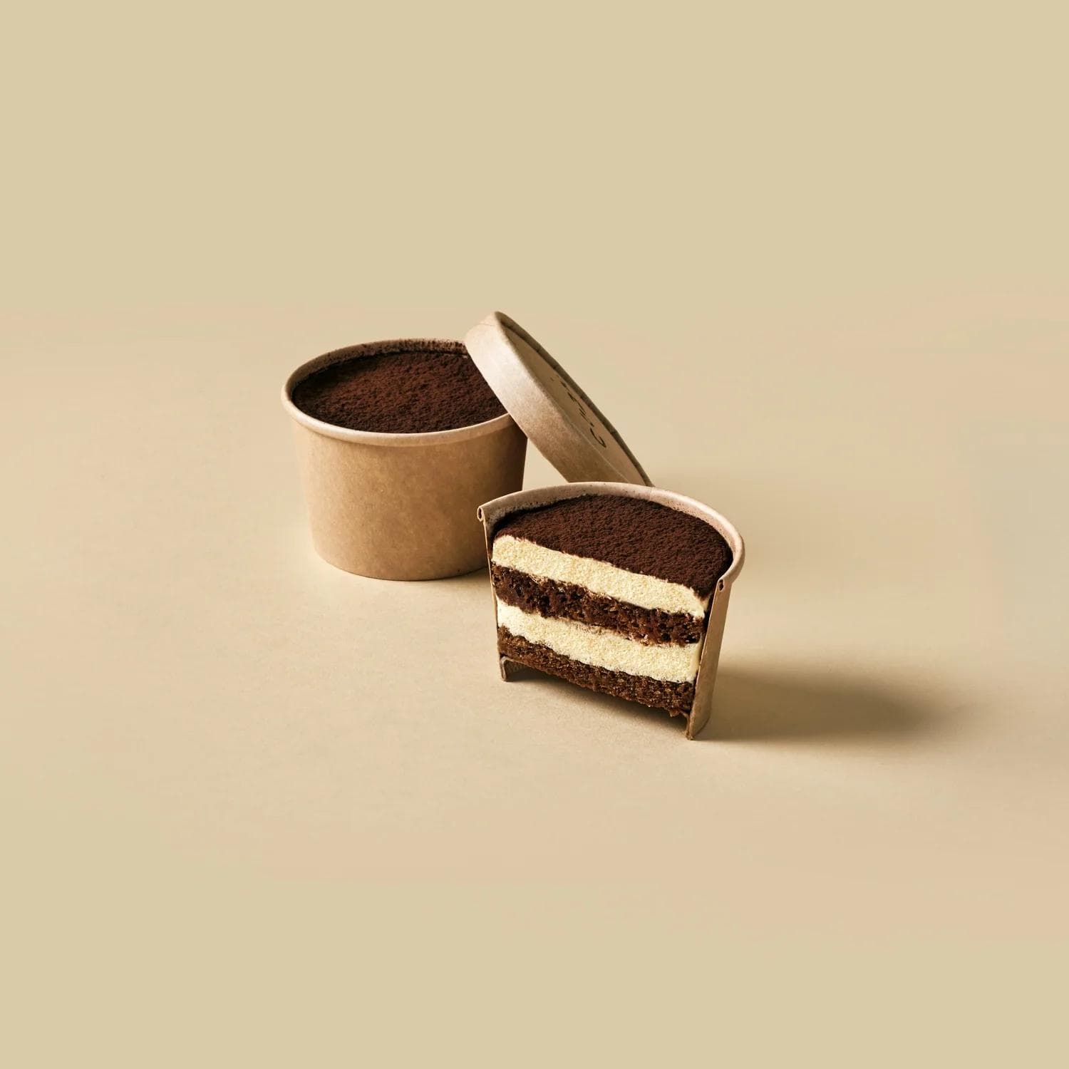 Tiramisu cup with slice cut showing layered cream and cocoa