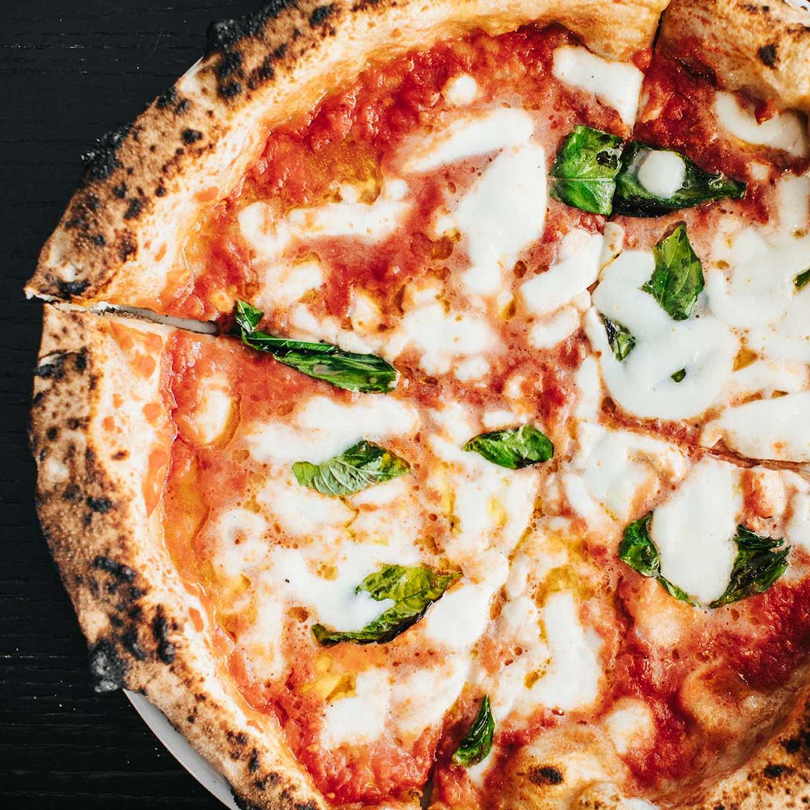 Close-up of margherita pizza with charred crust and fresh basil