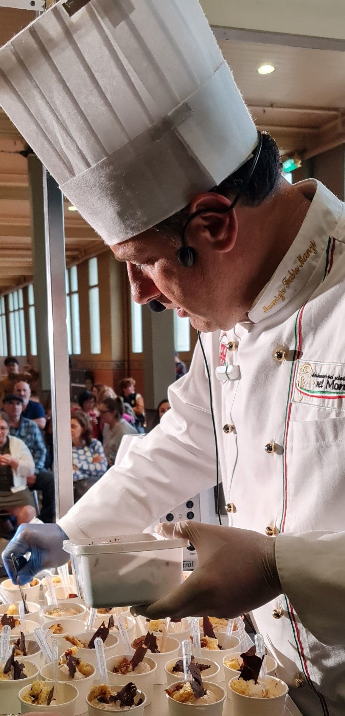 Maurizio Manzi in a chef's toque and whites, plating desserts