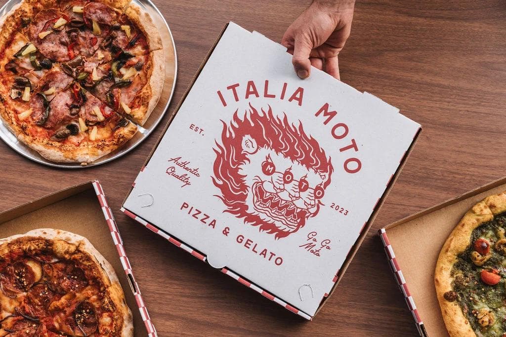Pizza box branded Italia Moto with pizzas on wooden table