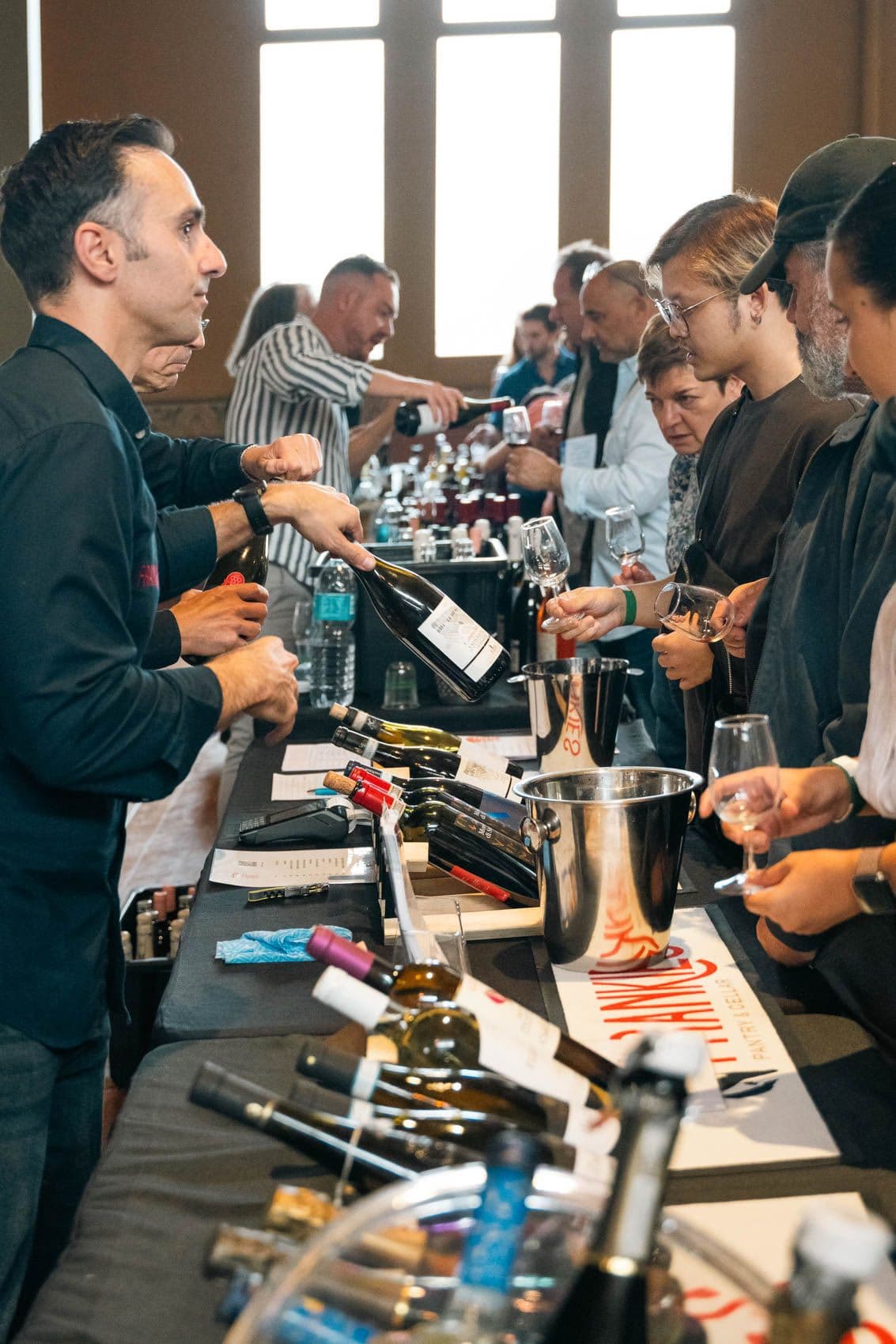 Wine presenter pouring sample for attendees at tasting event table