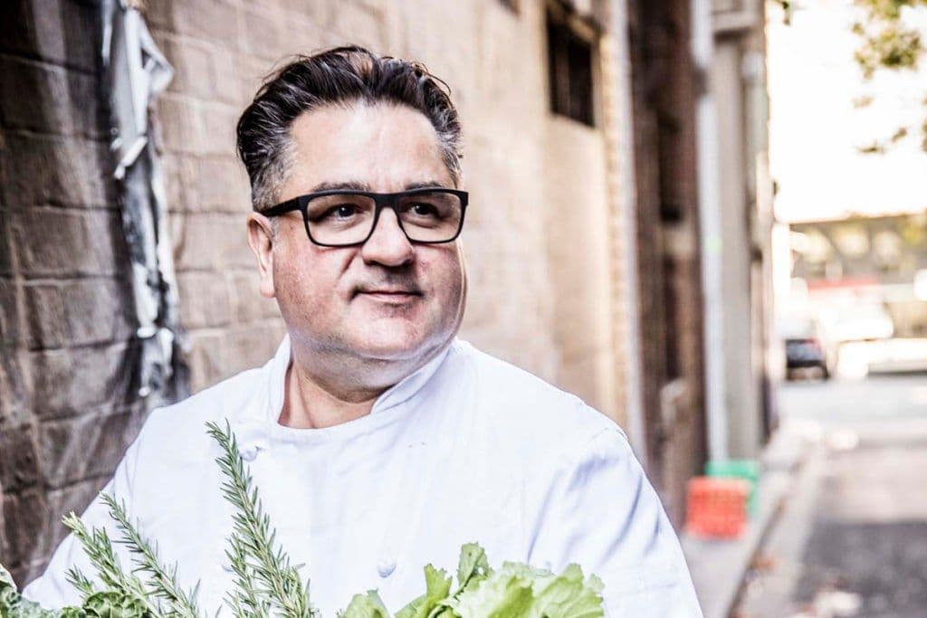Guy Grossi in chef's whites and glasses in a Melbourne laneway