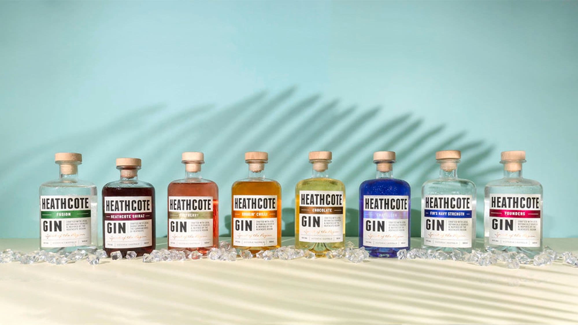 Row of colourful Heathcote Gin bottles on ice with shadows
