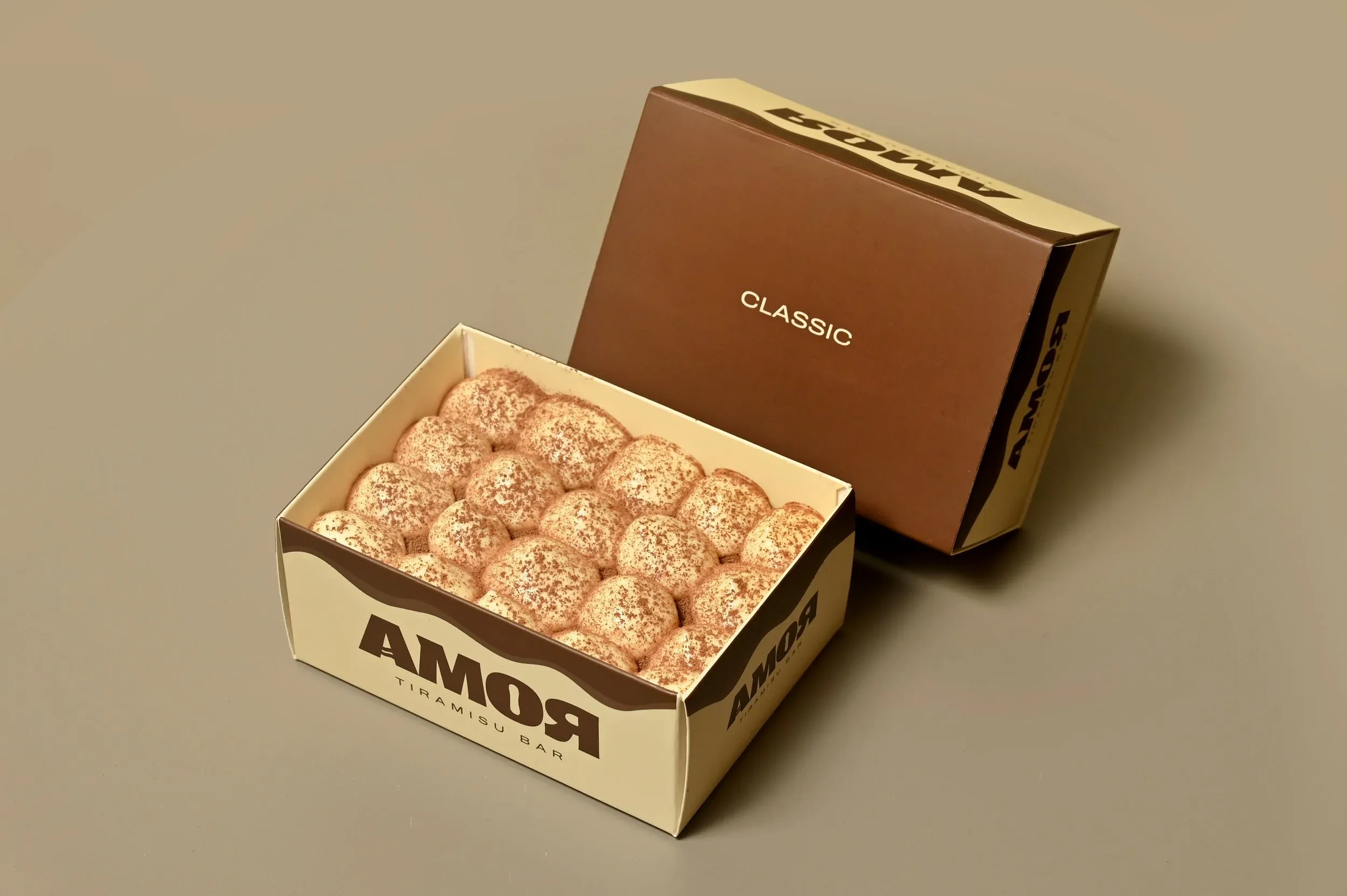 Open box of classic tiramisu bites with dusted cocoa powder