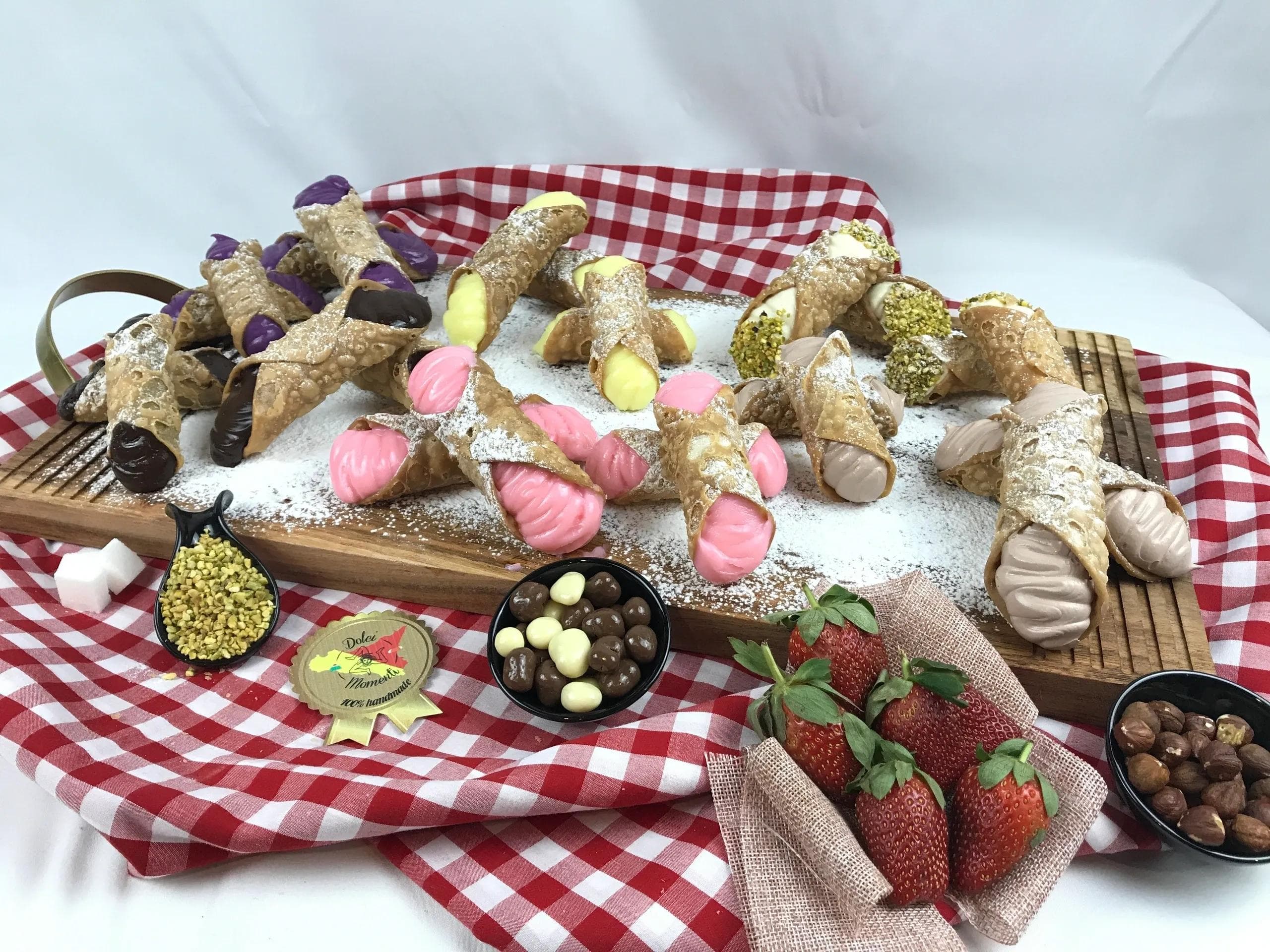 Assorted cannoli with colorful fillings on wooden board with strawberries