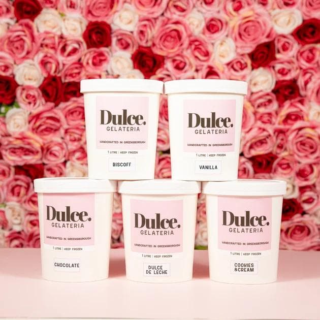 Five Dulce Gelateria pints stacked against a rose flower backdrop