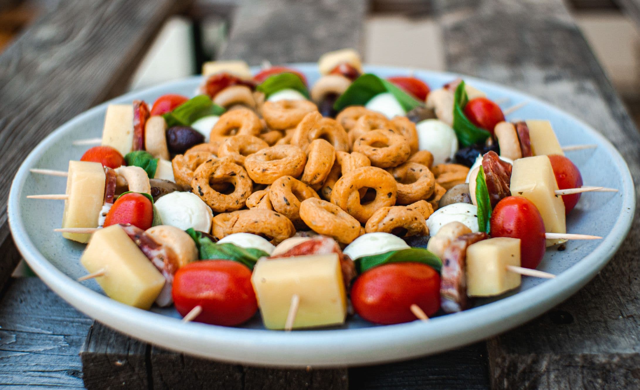Platter of taralli biscuits with cheese, tomatoes and mozzarella skewers