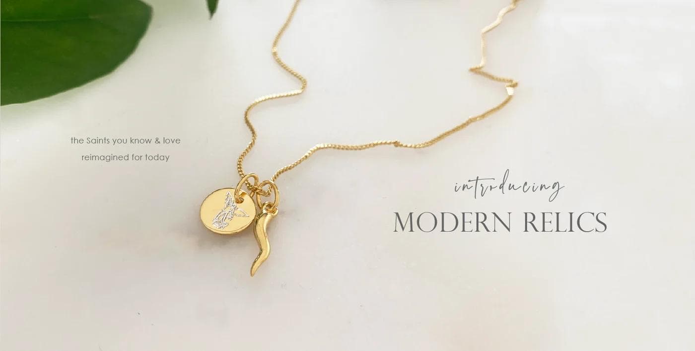 Gold necklace with charm pendants displayed on white surface
