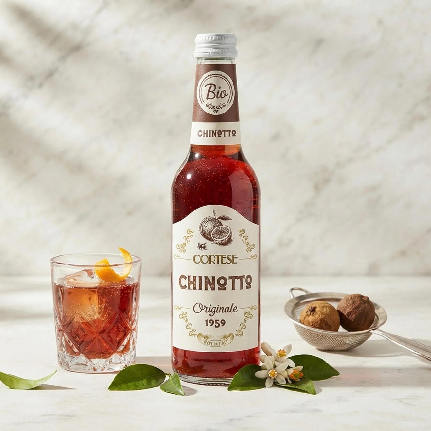 Cortese Chinotto bottle beside cocktail glass with orange twist
