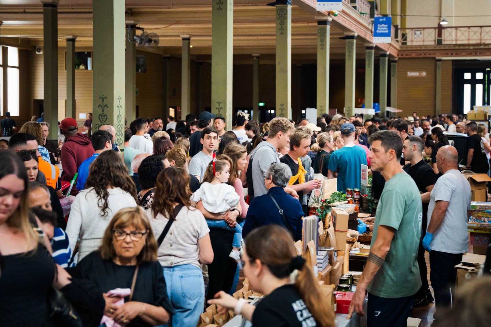 Crowded indoor festival venue with hundreds of visitors browsing vendor stalls