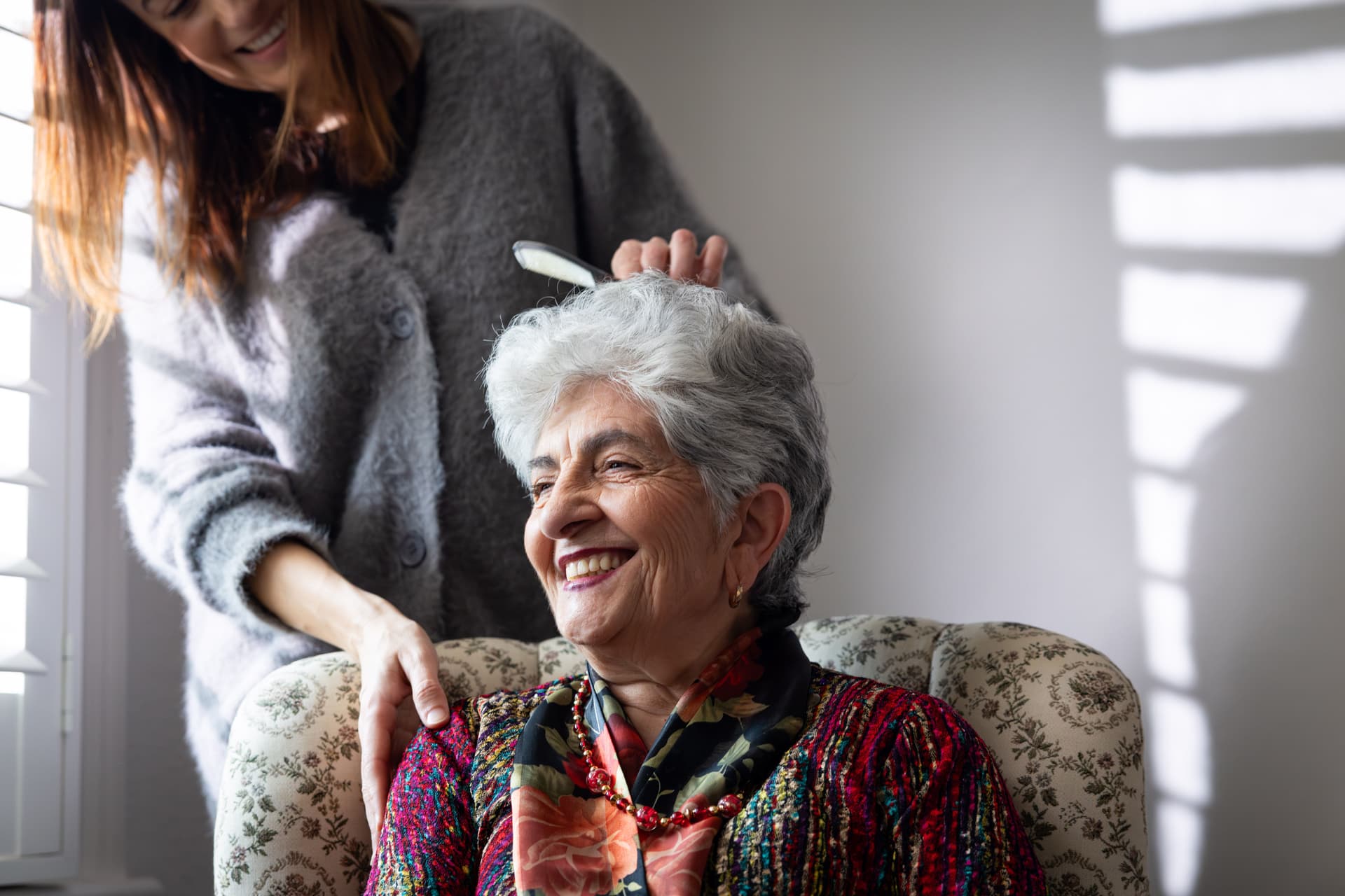 An older woman and a CO.AS.IT. staff member laughing together outdoors