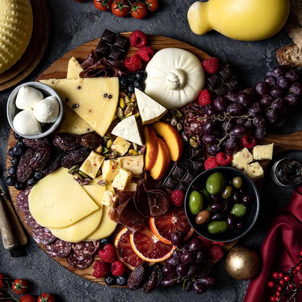 Cheese board with charcuterie, grapes, olives, chocolate and fruit