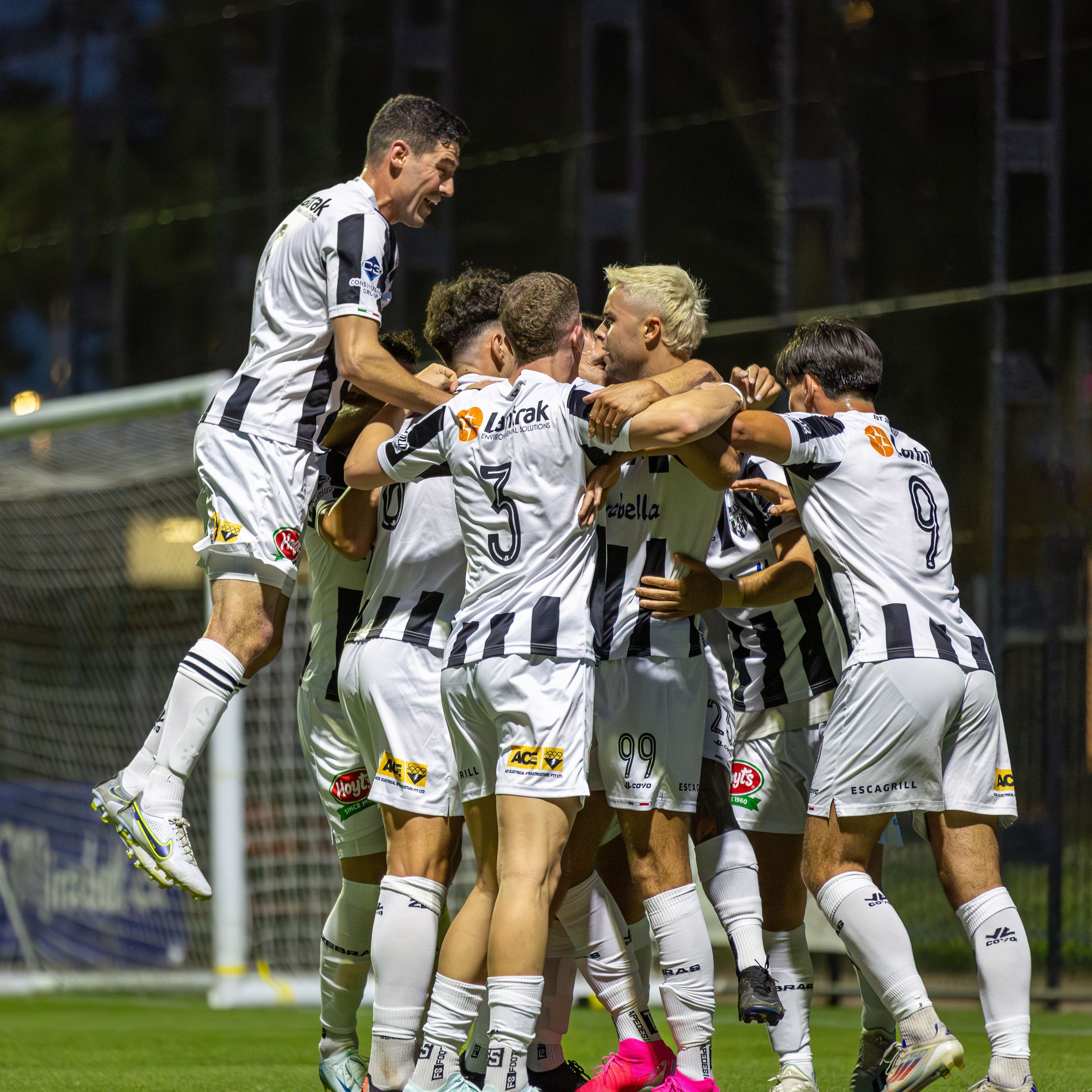 Players in black and white striped kits celebrating a goal together