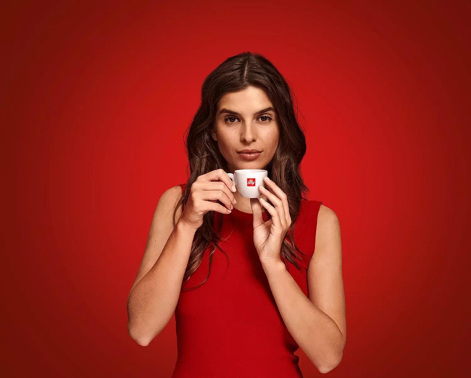 Woman in red holding small illy espresso cup
