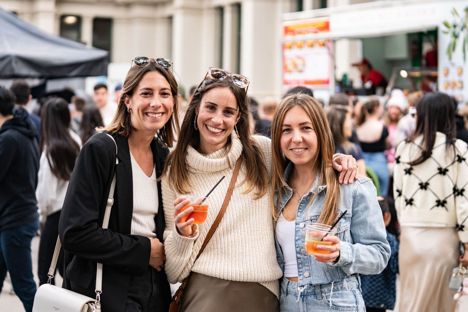 Three smiling women enjoying drinks at Melbourne Italian Festa outdoor celebration