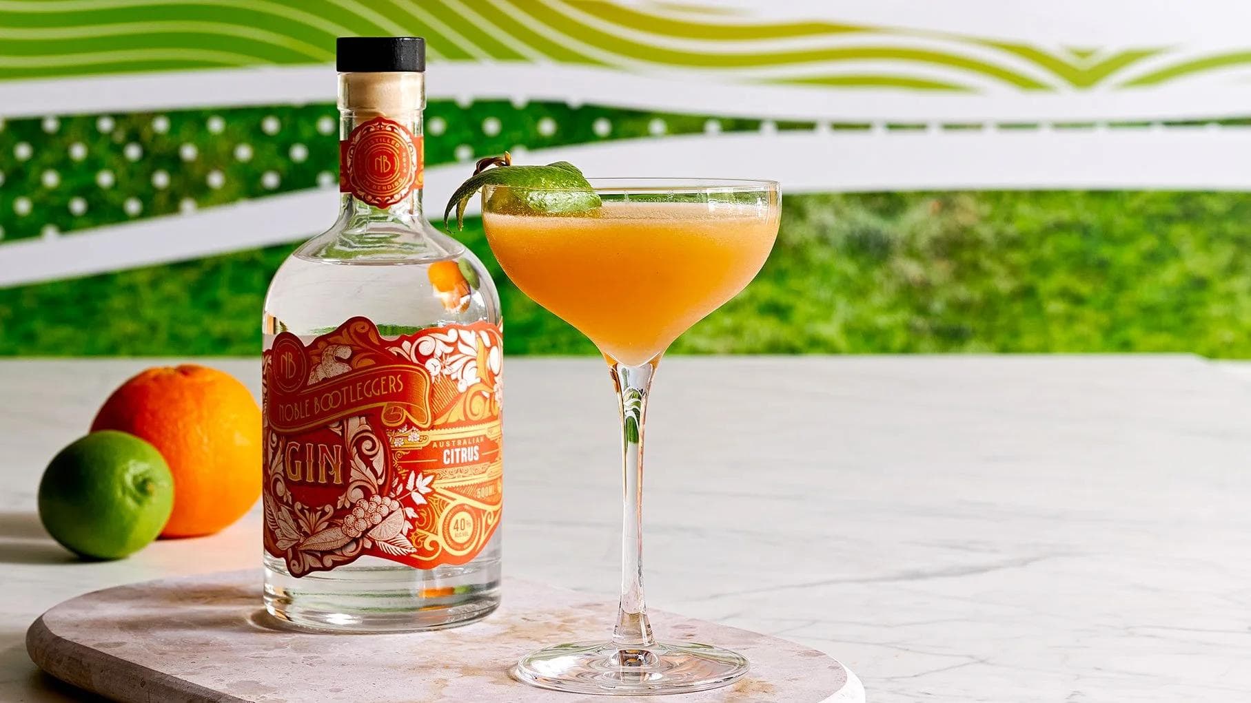Gin bottle with citrus cocktail, orange and lime on marble