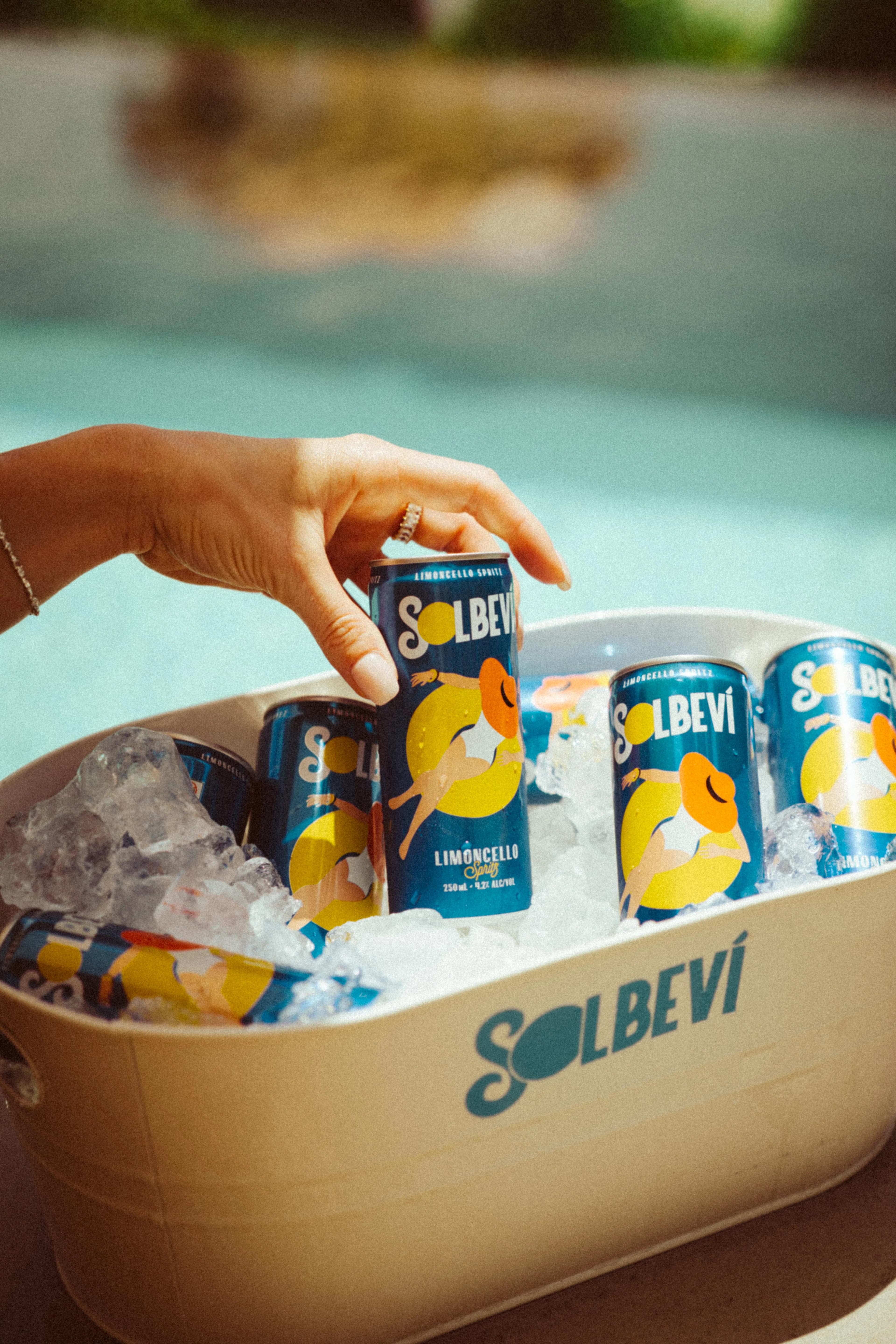 Hand grabbing Solbevi limoncello spritz can from ice bucket poolside