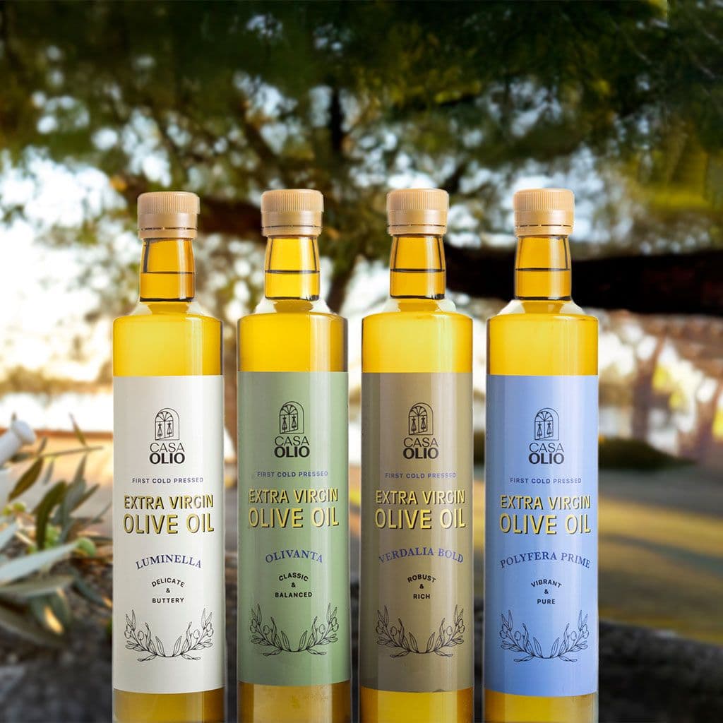 Four Casa Olio extra virgin olive oil bottles with labeled varieties outdoors