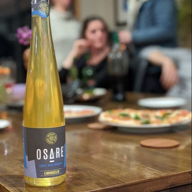 Bottle of Osare limoncello on table with pizza background