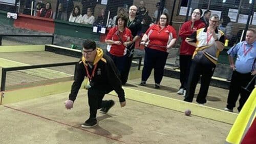 Player mid-throw during bocce championship match on indoor court