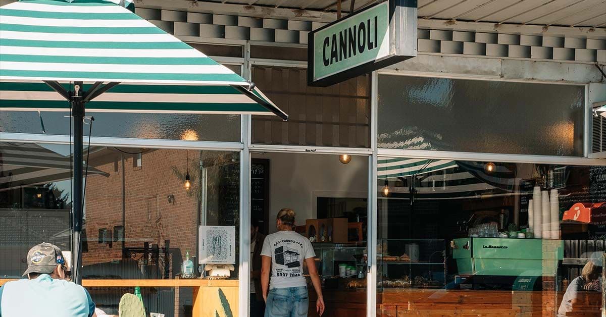 Cannoli Bar shopfront with green striped umbrella and sign