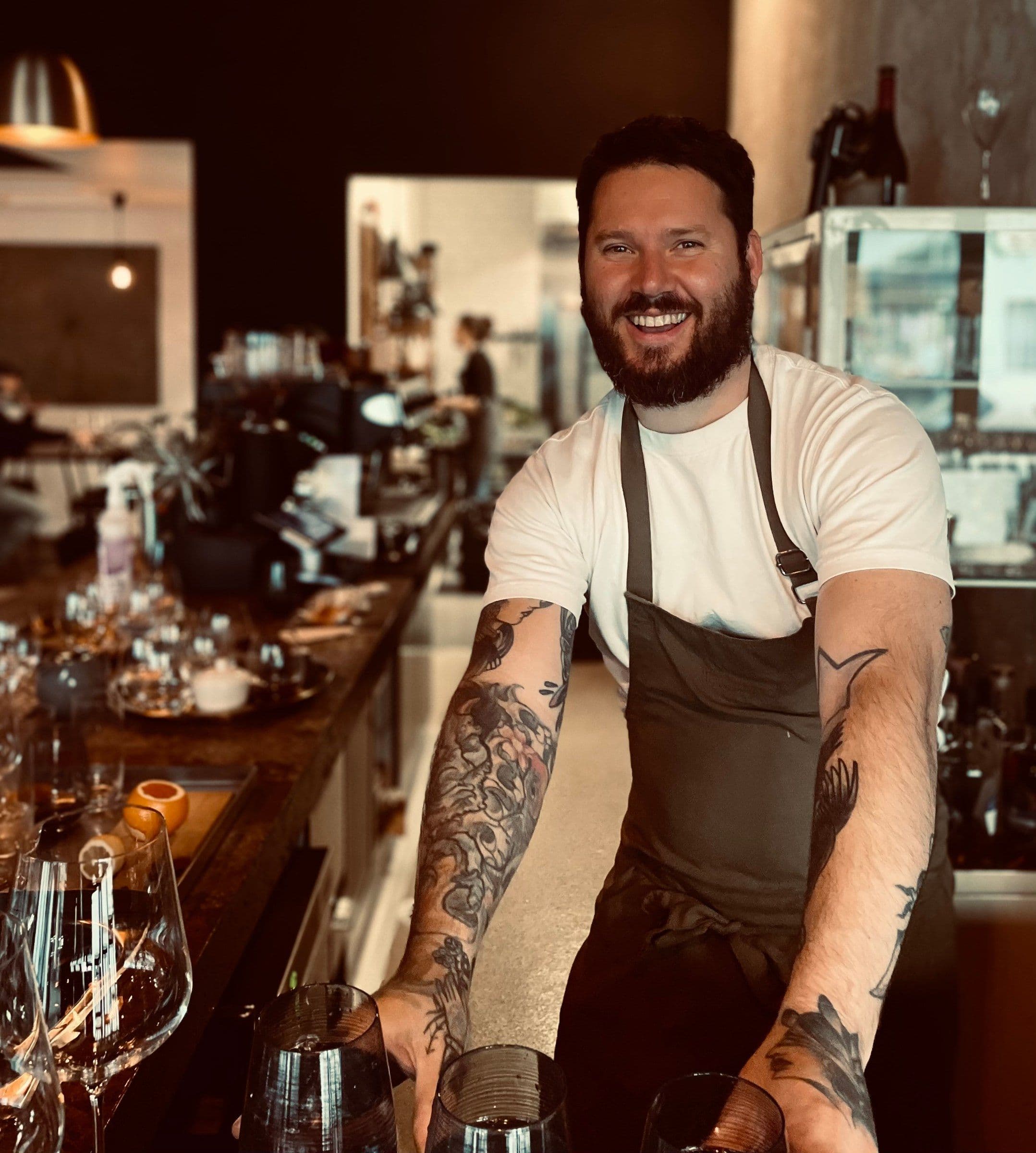 Nicola Romano smiling in a brown apron behind a restaurant bar