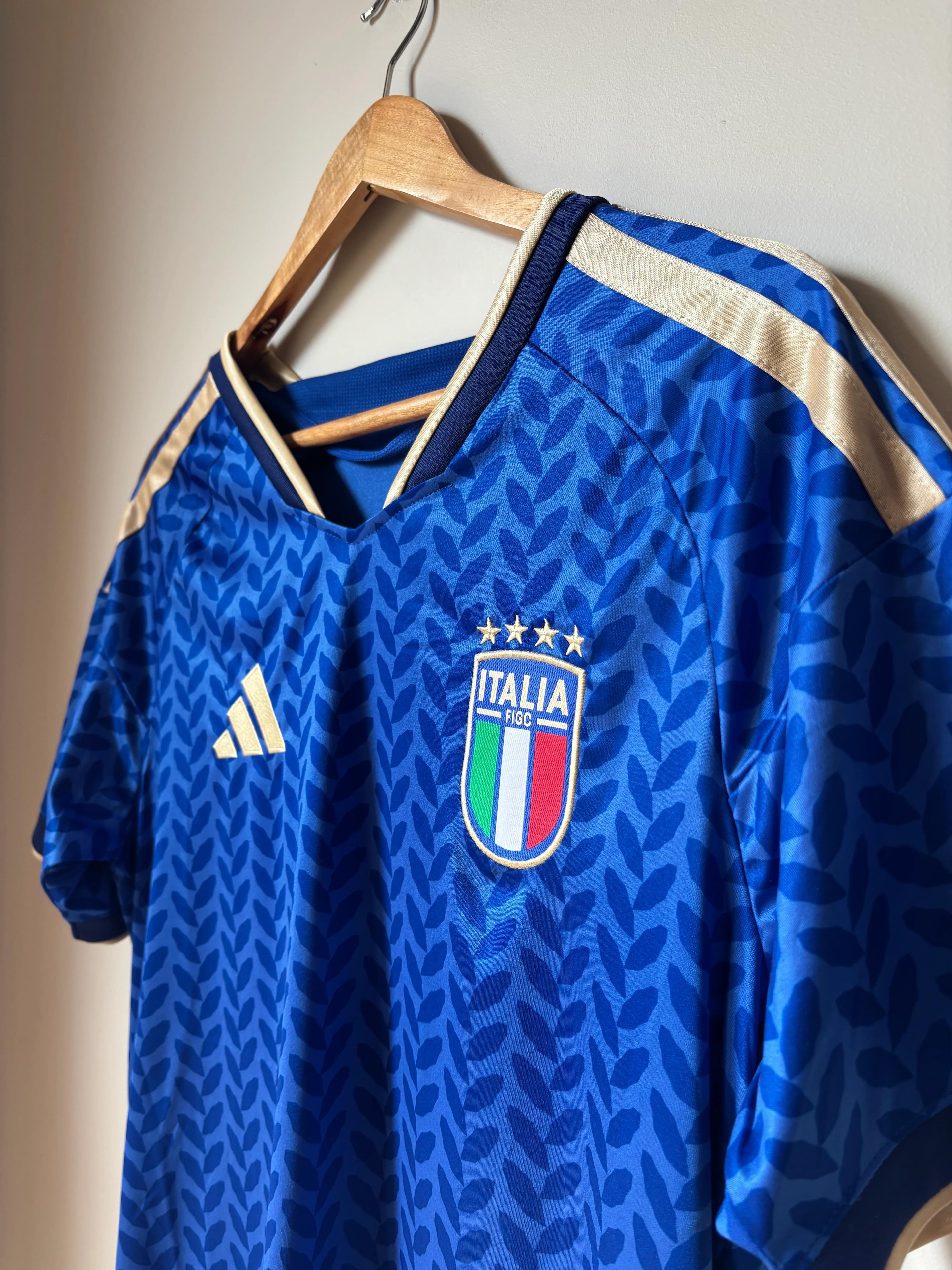 Blue Italia football jersey with gold trim on wooden hanger