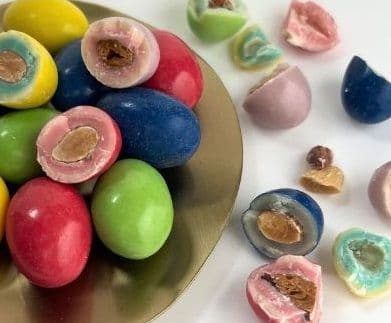 Colourful sugared almonds piled on gold plate with cut pieces